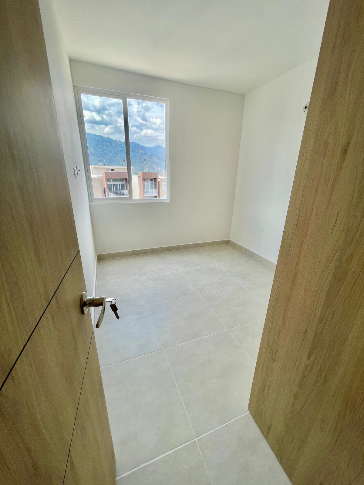 Habitación vacía vista desde la puerta, con ventana y vista a las montañas