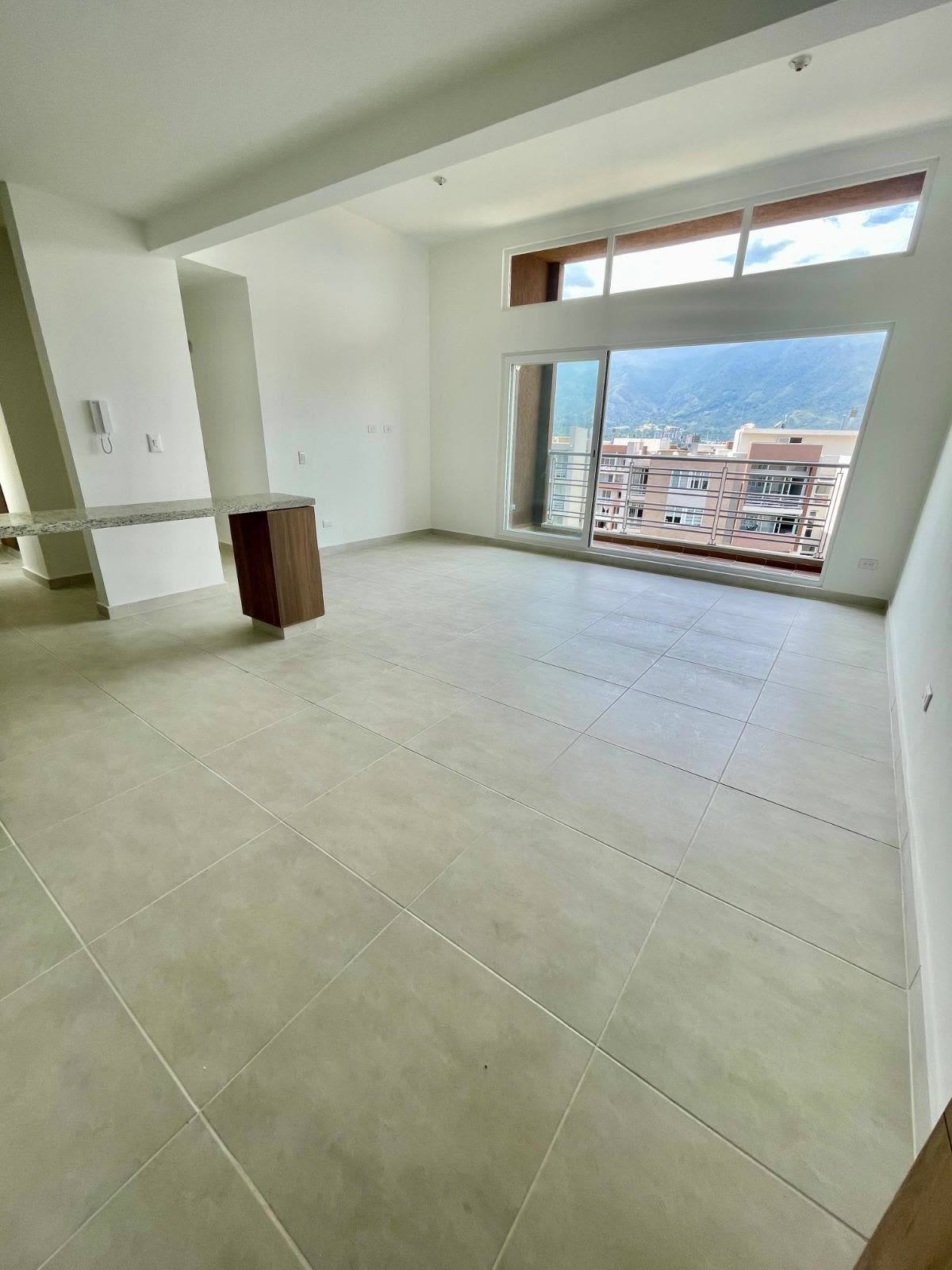Sala-comedor vacía con puerta corrediza al balcón y vista a las montañas